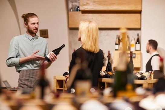 Agent commercial qui tient une bouteille de vin en main et qui conseille une cliente