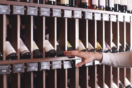 Rayon de bouteilles de vin dans un magasin, une main prend une bouteille