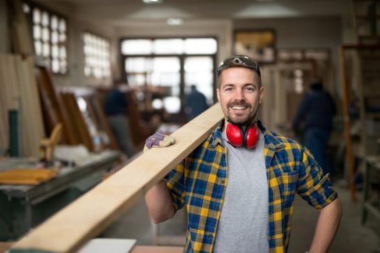 Menuisier adulte qui tient une planche sur son épaule