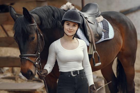 Cavalière à pied qui tient son cheval par les rennes 
