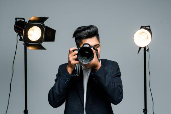 Photographe dans un studio photo avec un fond gris et deux lampes