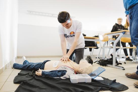Jeune homme qui procède à un massage cardiaque sur un manequin