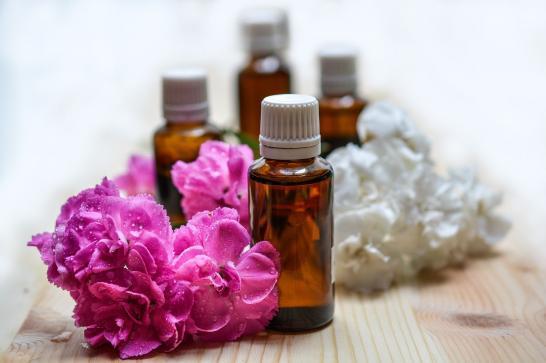 Flacons d'huiles essentielles avec une décoration florale en rose fuschia et blanc