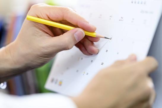 Personne qui pointe une date sur un calendrier avec un crayon