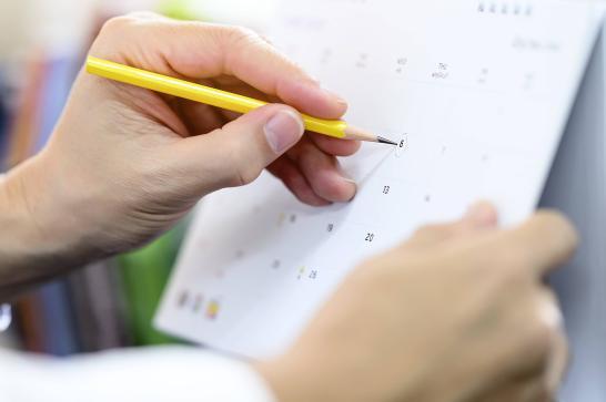 Personne qui pointe une date sur un calendrier avec un crayon