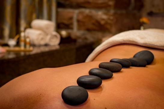 Scène de massage avec des galets noirs posés sur un dos