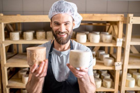 Jeune homme fromager qui tient deux de ses fromages en main