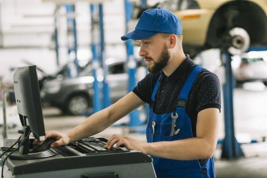 Mécanicien qui vérifie le diagnostic d'une panne de voiture sur l'ordinateur dans un garage