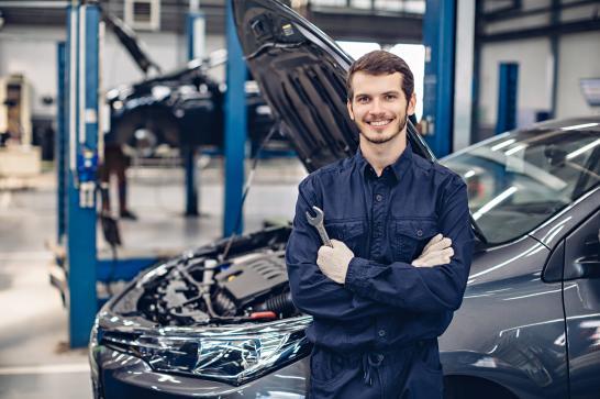 Mécanicien qui pose devant une voiture dans un garage automobile