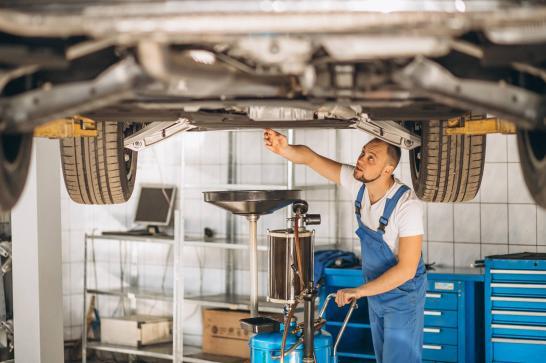 Mécanicien automobile qui effectue la vidange d'un véhicule