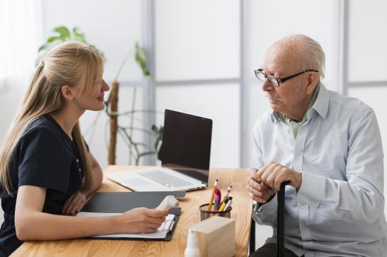 Directrice de maison de repos qui remet un médicament à un vieux monsieur dans son bureau