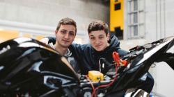2 apprenants appuyés sur une moto de course