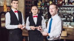 Chef de rang qui donne ses instructions à deux serveurs avant le service dans un restaurant