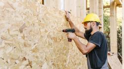 Ouvrier qui fixe une paroi en bois sur une structure de maison en bois