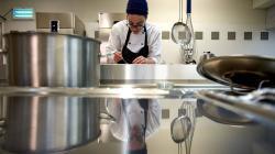 Manageuse de produit culinaire qui prépare son plat dans une cuisine professionnelle