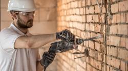 Ouvrier qui fait une saignée dans un mur de brique dans une maison en rénovaton
